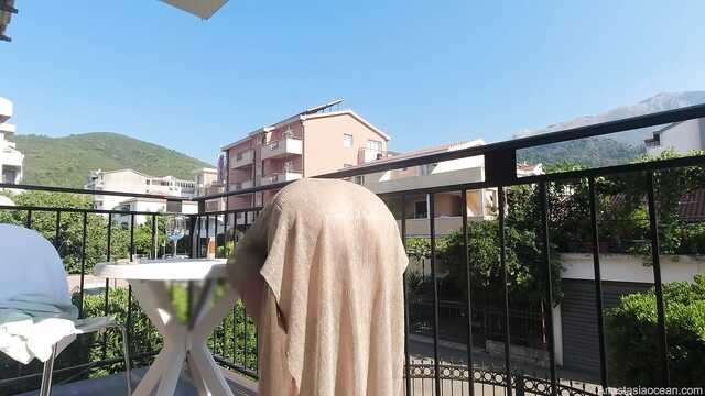 Высокая женщина без белья позирует на балконе