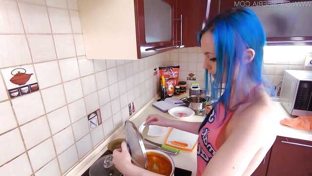 Dziewczyna z niebieskimi włosami na kuchennym stole wali szczelinę ogórkiem